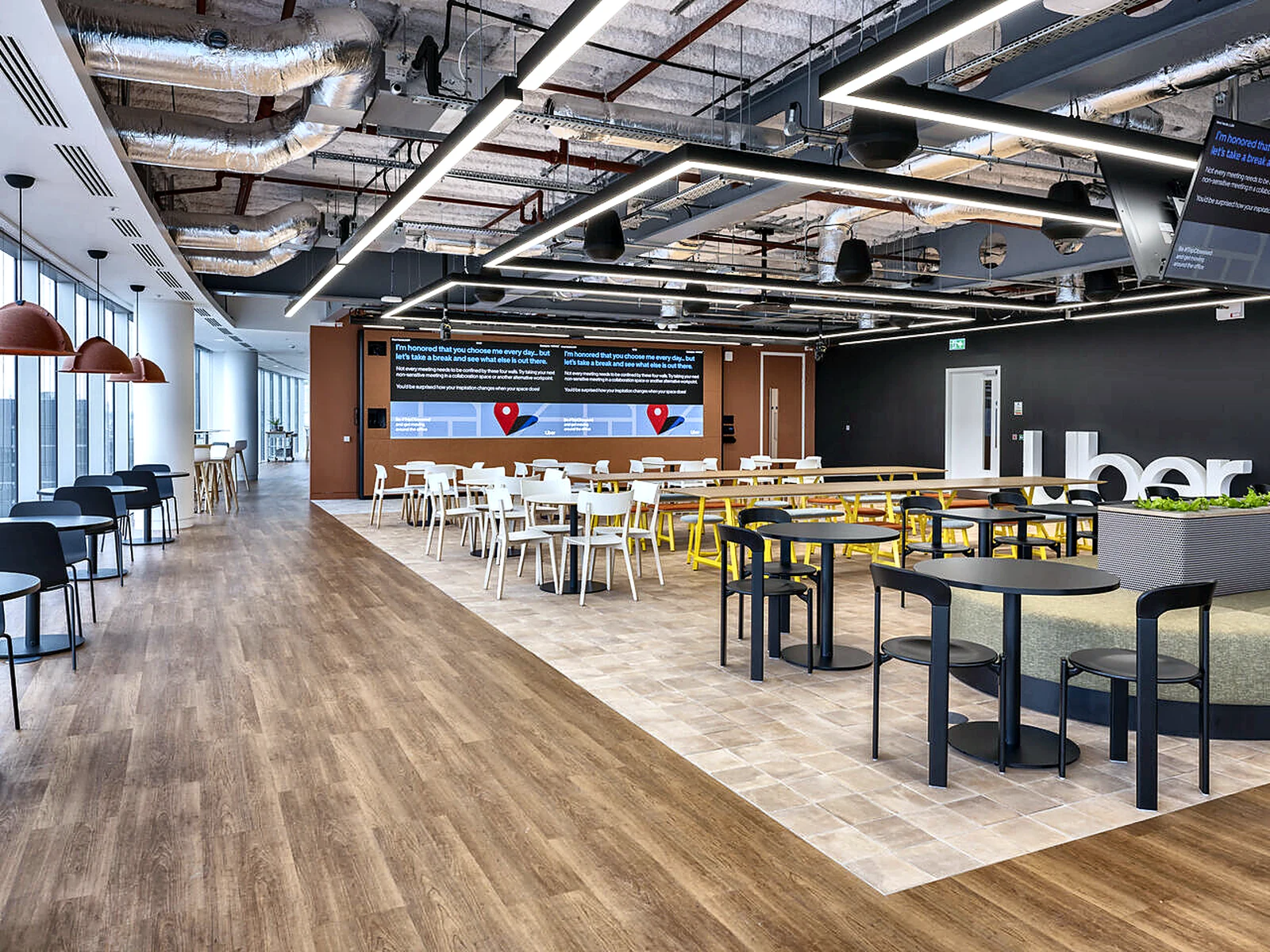 Breakout and dining area at Uber HQ beneath a dark exposed-services ceiling