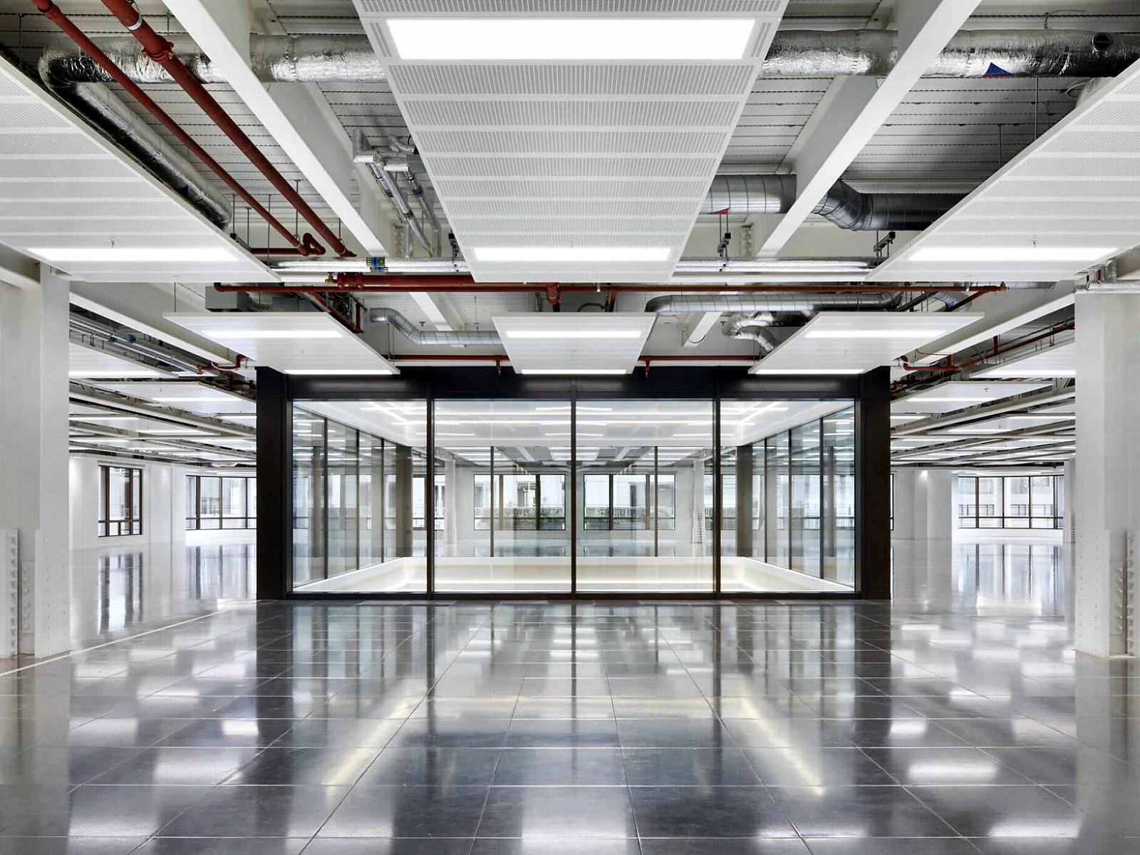 Vacant office floor at Woolgate Exchange with white ceiling rafts, exposed services and a glazed meeting room